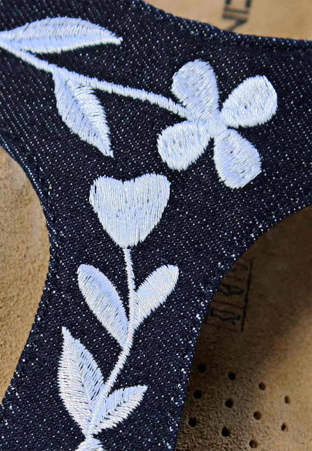 Nahaufnahme von Pantolette mit Jeans-Riemen und Blumenmuster